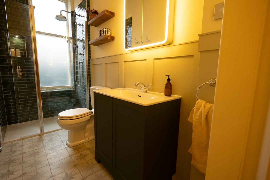 Small bathroom with an oak vanity, brass tap and white basin