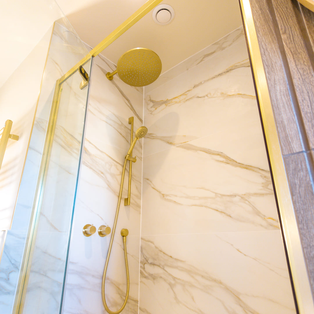 Walk-in shower with brass rainfall head and Calacatta marble tiling